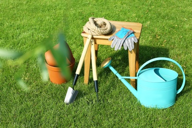 Photo of Set of gardening tools and stool on green grass