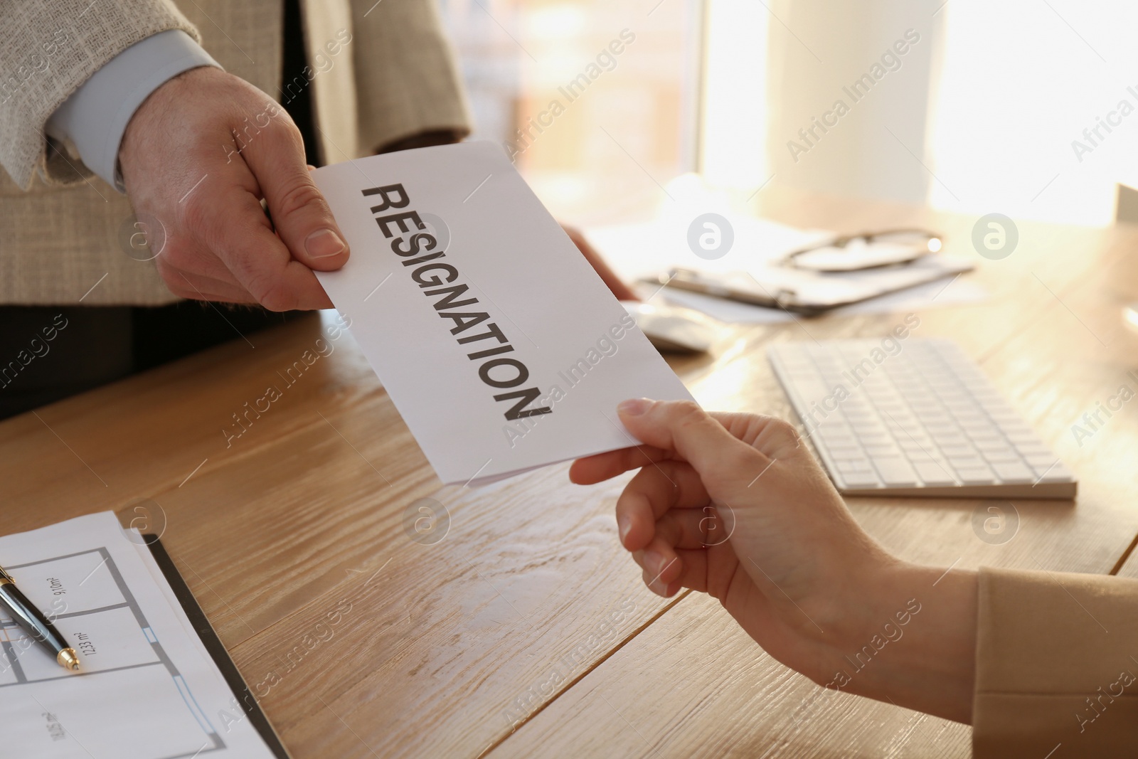 Photo of Employee giving resignation letter to boss in office, closeup