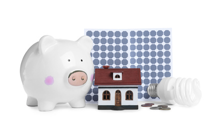 Photo of Composition with solar panels and piggy bank on white background