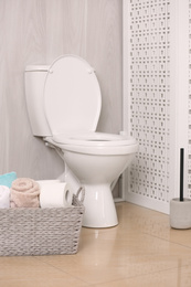 Photo of White toilet bowl near folding screen in bathroom