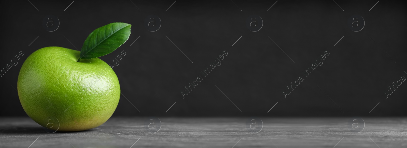 Image of Fresh ripe sweetie with green leaf on grey table, space for text. Banner design