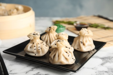 Plate with tasty baozi dumplings on marble table