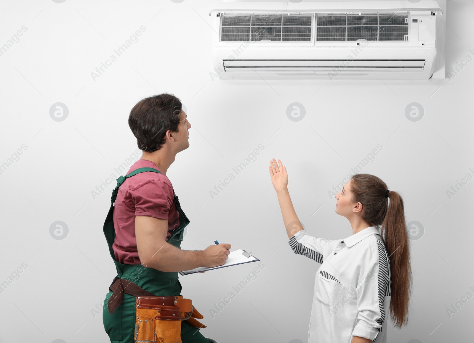 Photo of Male technician speaking with woman about air conditioner indoors