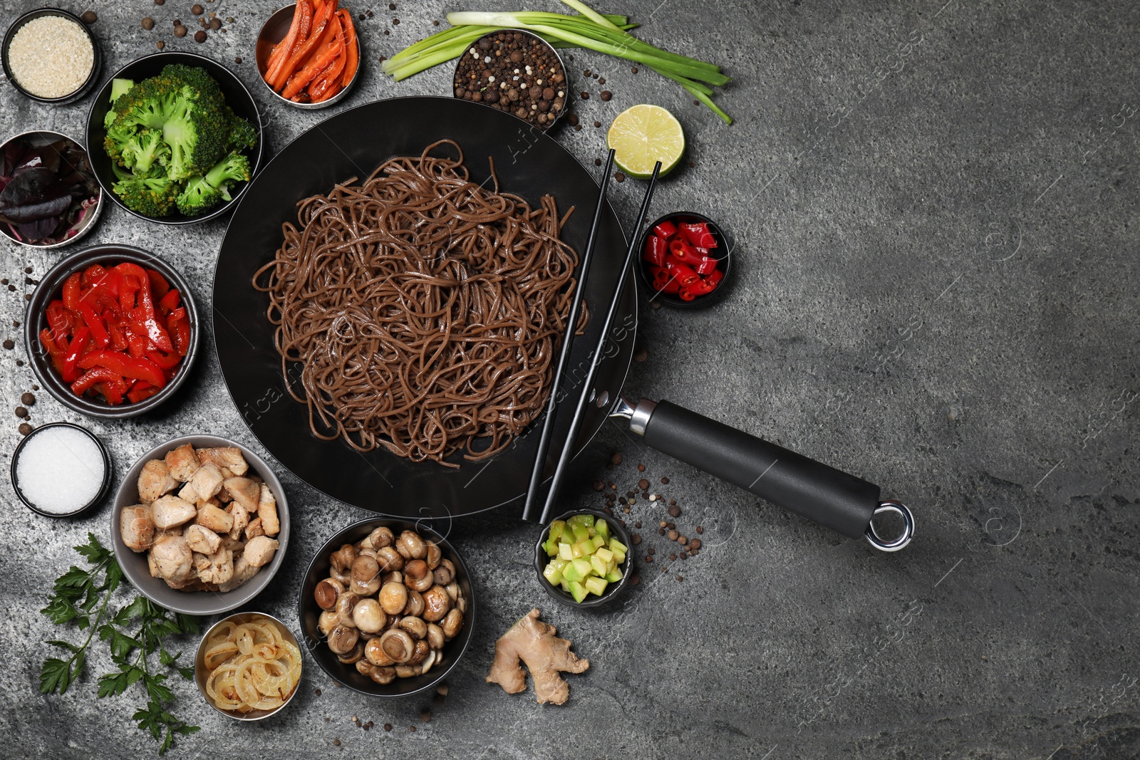 Photo of Wok with noodles, chicken and other products on grey table, flat lay. Space for text