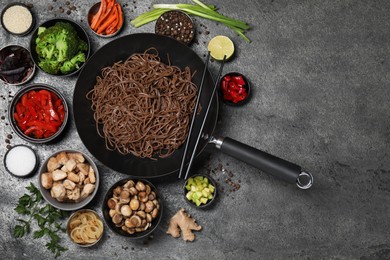 Wok with noodles, chicken and other products on grey table, flat lay. Space for text