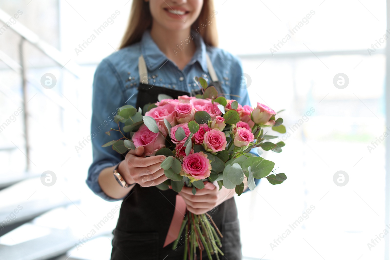 Photo of Female florist holding bouquet of beautiful flowers, indoors