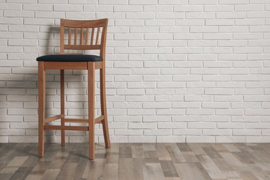 Stylish bar stool near white brick wall indoors. Space for text