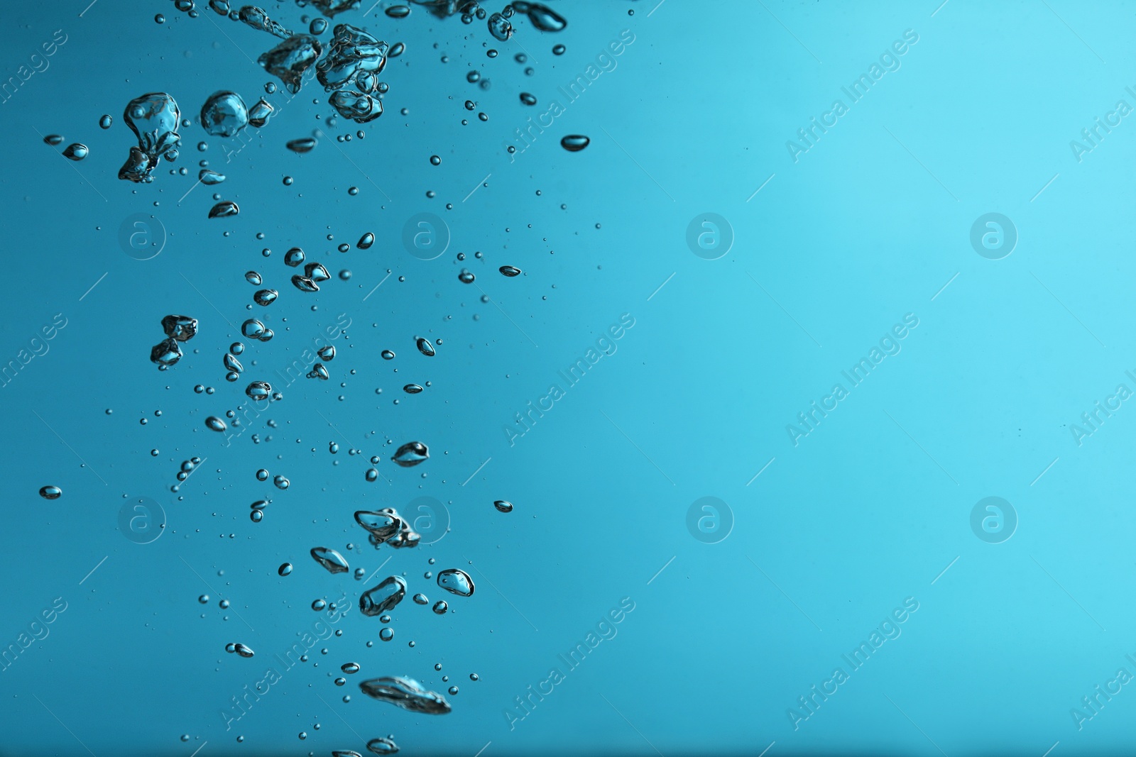 Photo of Air bubbles in water on blue background. Space for text