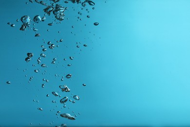 Photo of Air bubbles in water on blue background. Space for text