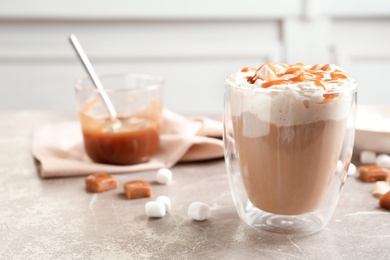 Cup of coffee with caramel topping on grey table