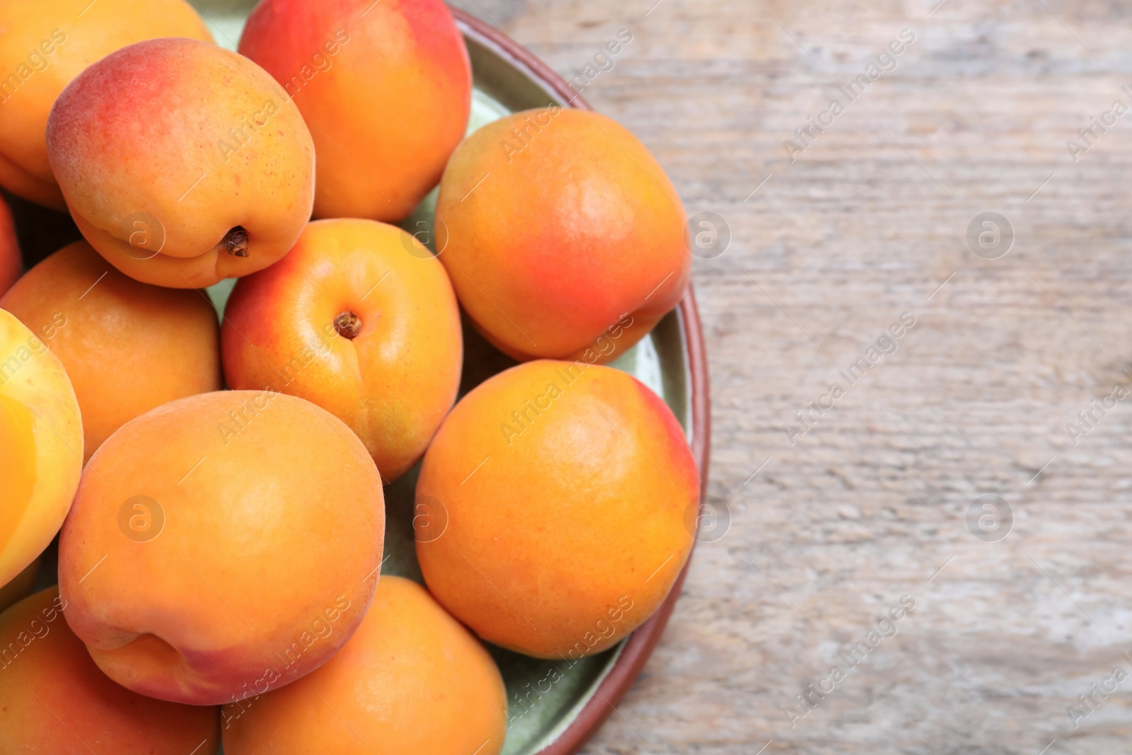 Photo of Delicious fresh ripe apricots on wooden table, top view. Space for text