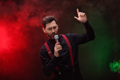 Emotional man with microphone singing in color lights