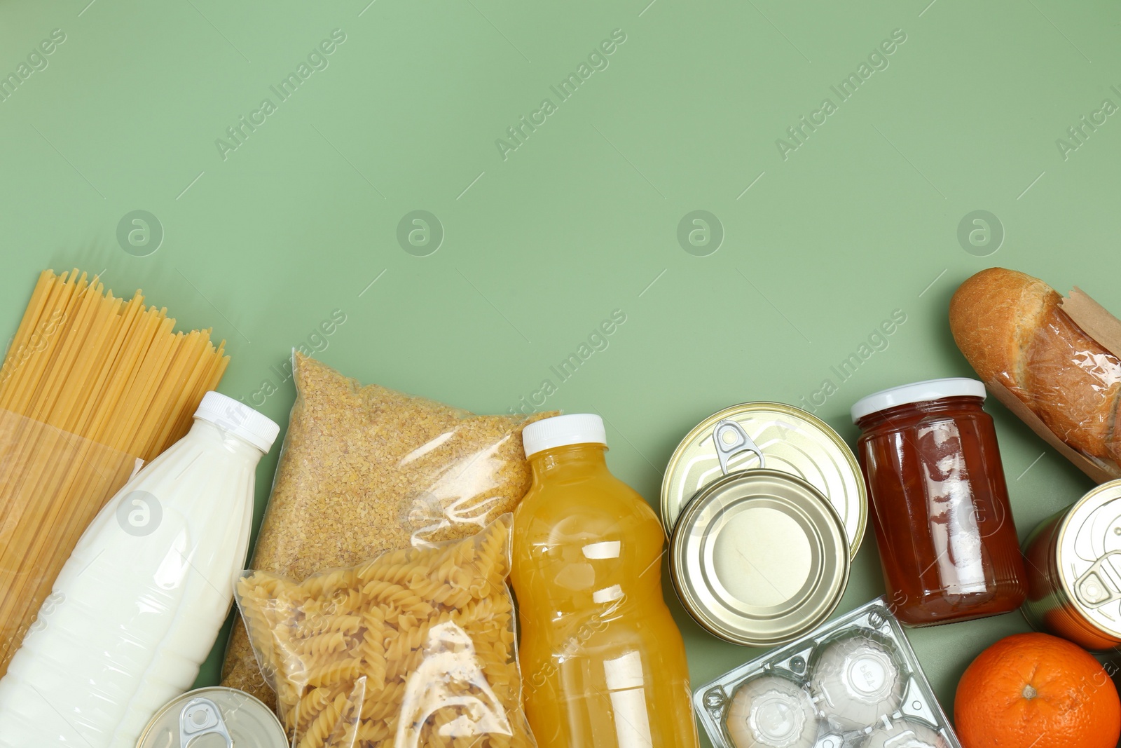 Photo of Humanitarian aid. Different food products for donation on green background, flat lay. Space for text