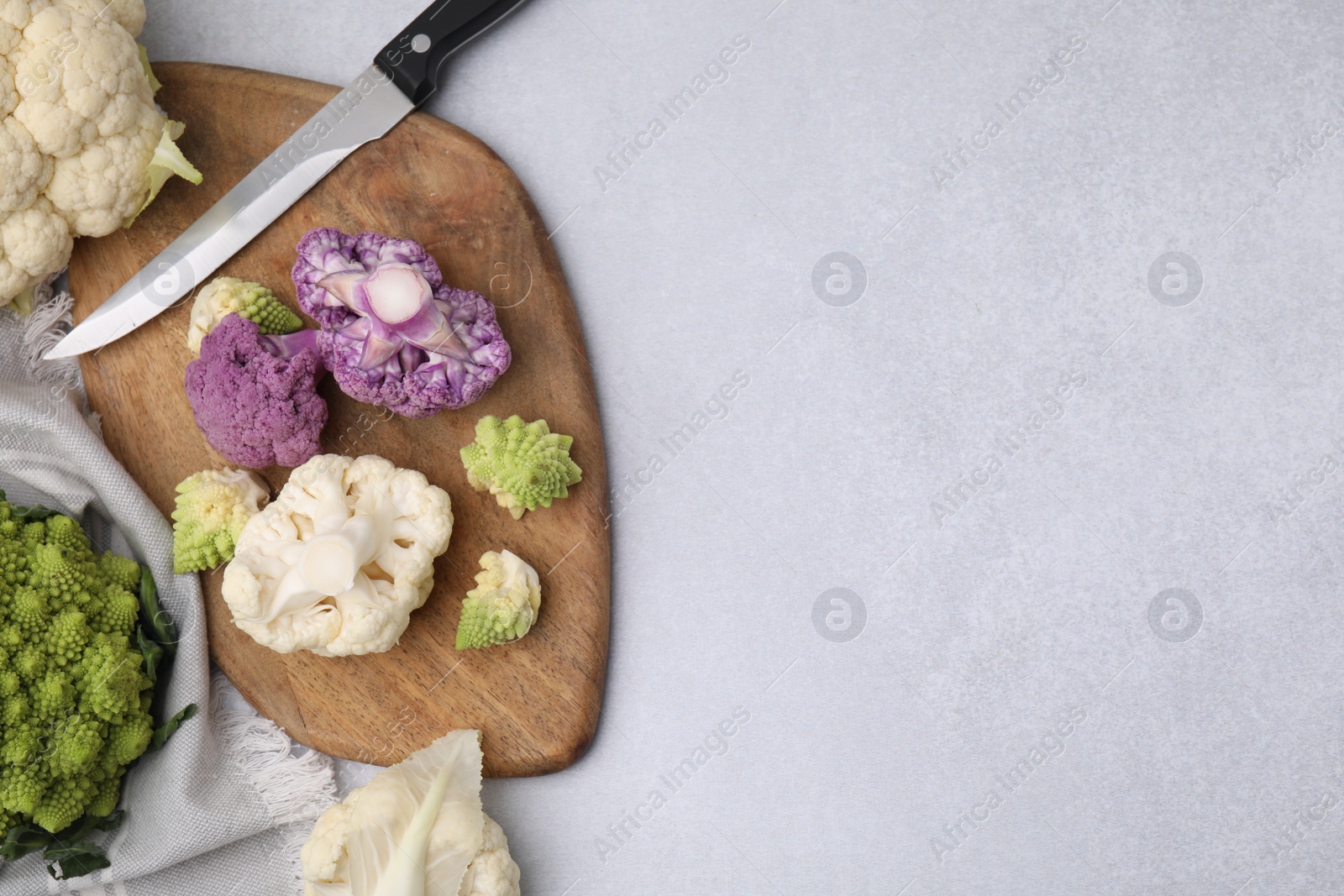 Photo of Various cauliflower cabbages on light grey table, flat lay. Space for text