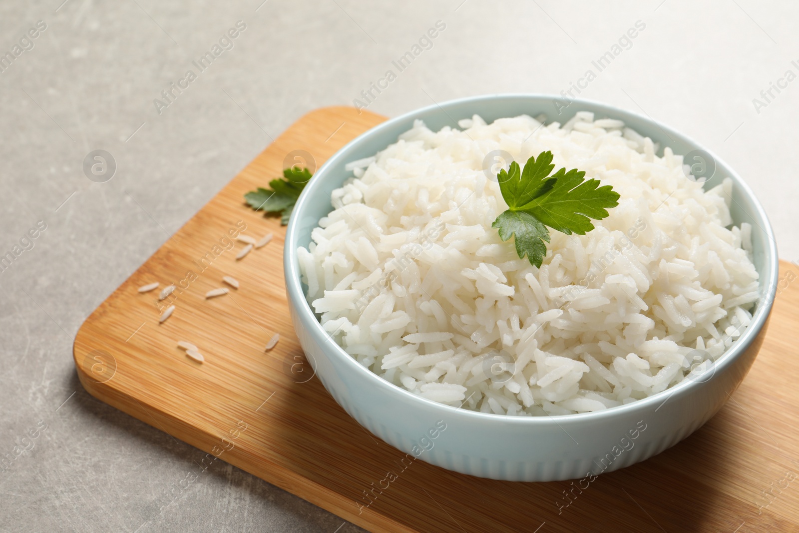 Photo of Bowl of delicious rice with parsley on table, space for text