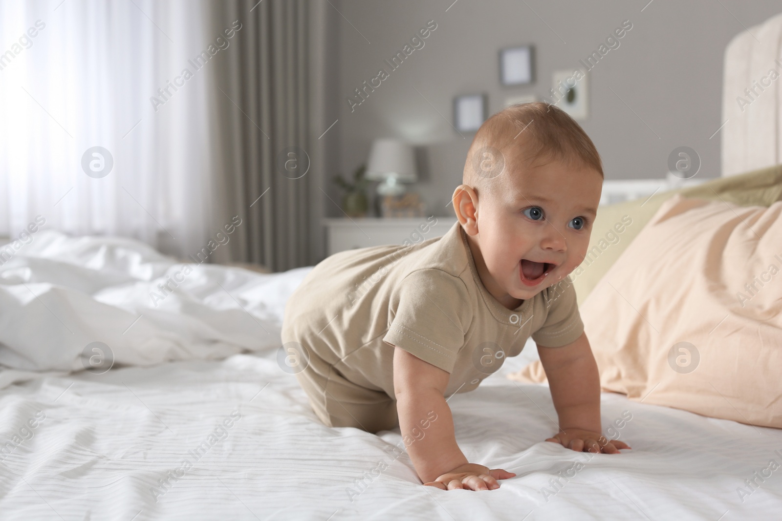 Photo of Cute baby crawling on bed at home