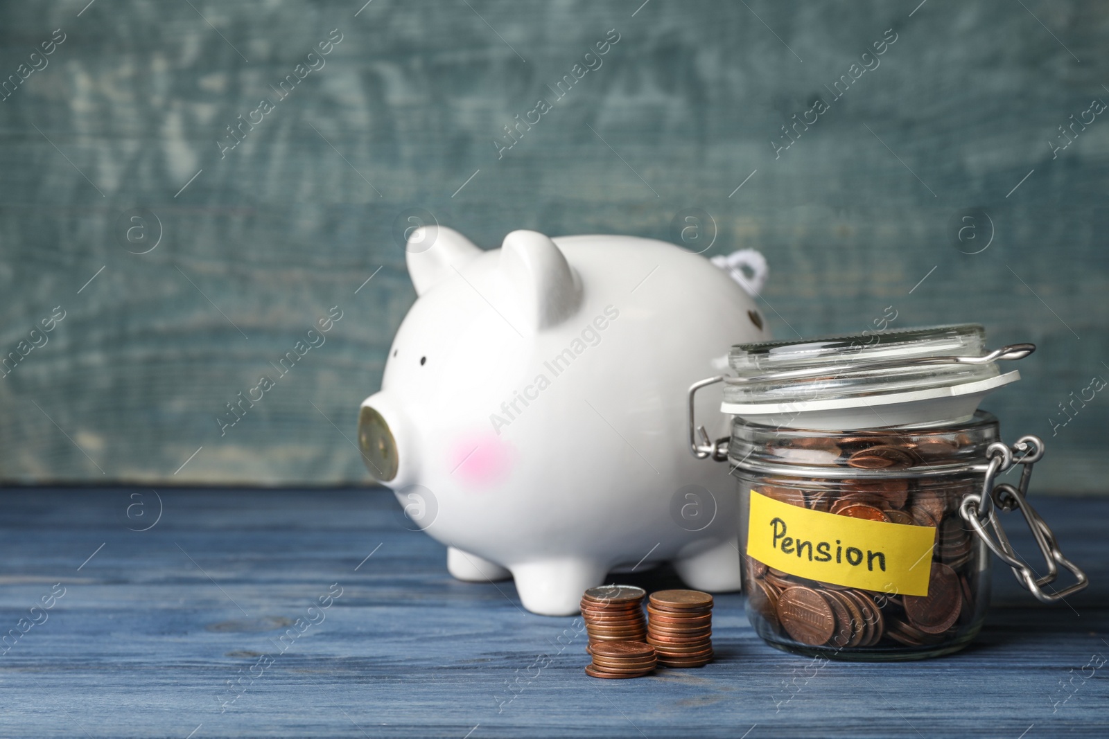 Photo of Piggy bank and jar of coins with word PENSION on table. Space for text