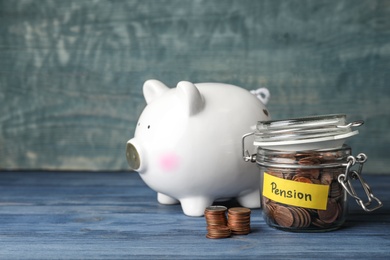 Photo of Piggy bank and jar of coins with word PENSION on table. Space for text