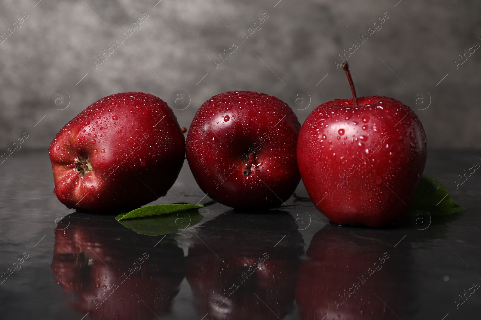 Photo of Wet red apples on dark grey table