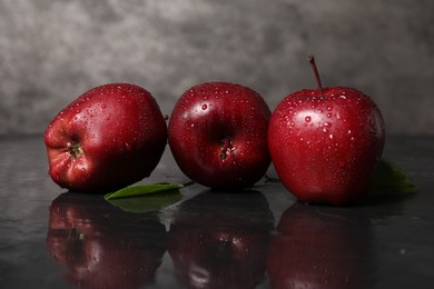 Wet red apples on dark grey table