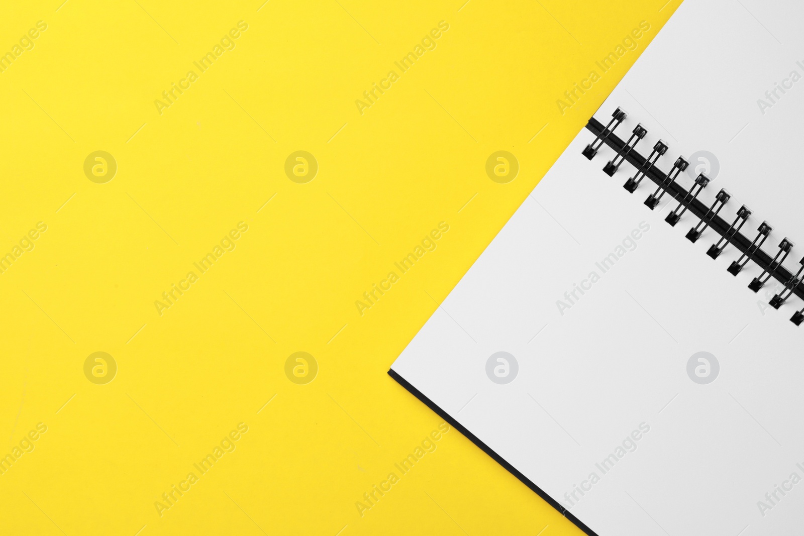 Photo of Blank notebook on yellow background, top view. Space for text