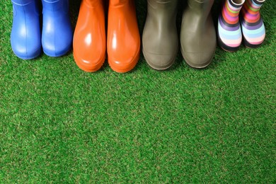 Photo of Rainboots for all family members on green grass, above view