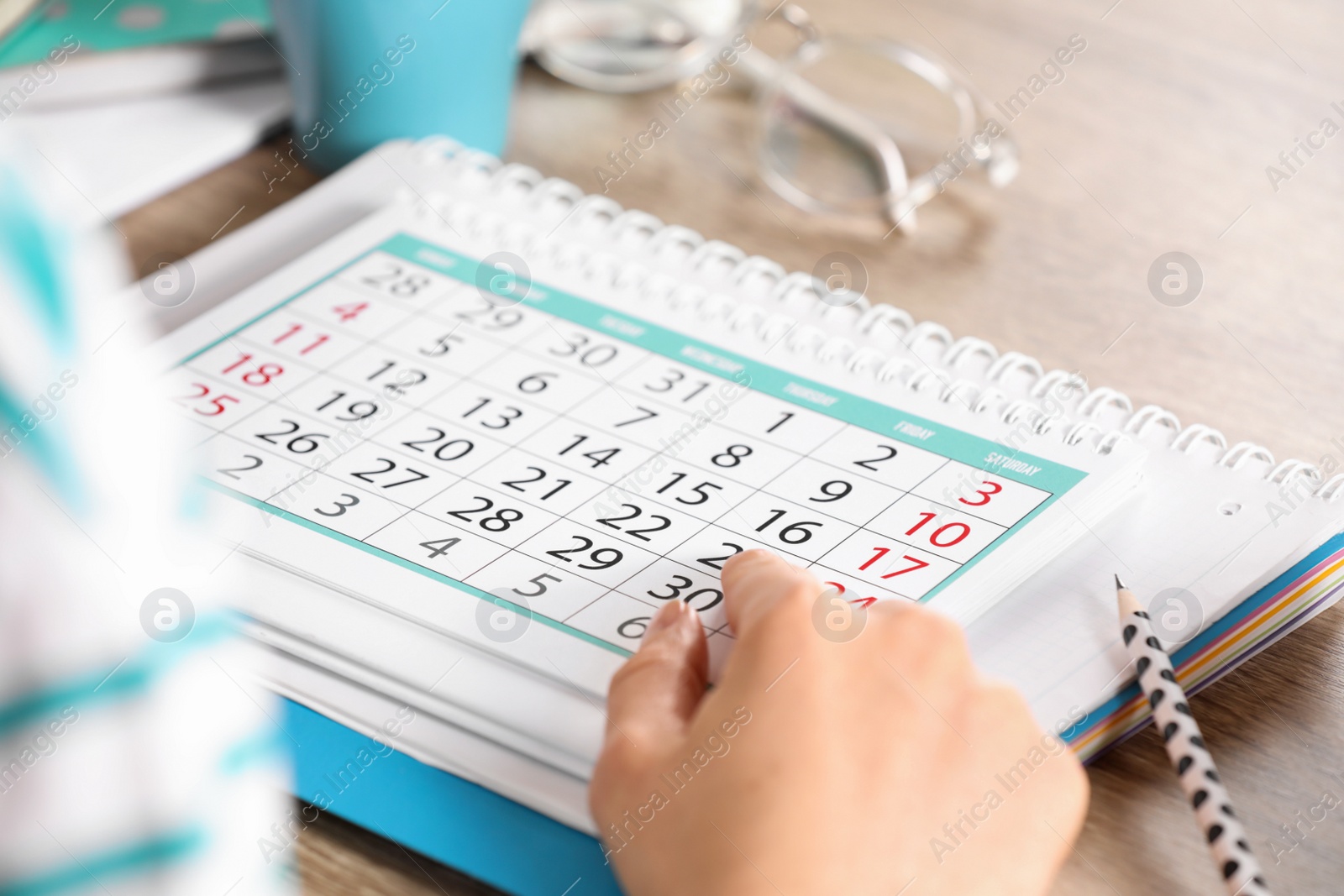 Photo of Woman with calendar at wooden table, closeup