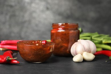 Photo of Tasty rhubarb sauce and ingredients on black table, space for text