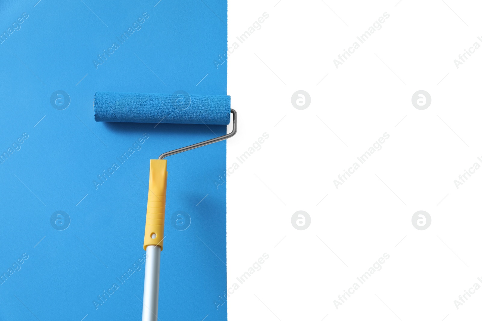 Photo of Applying light blue paint with roller brush on white wall