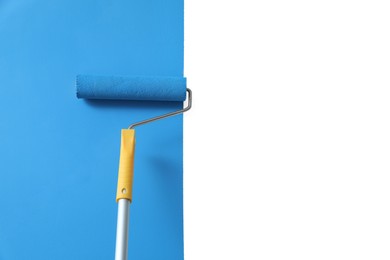 Photo of Applying light blue paint with roller brush on white wall