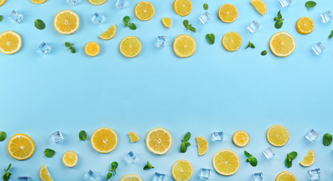 Photo of Frame made of lemon slices, mint and ice on light blue background, top view with space for text. Lemonade layout