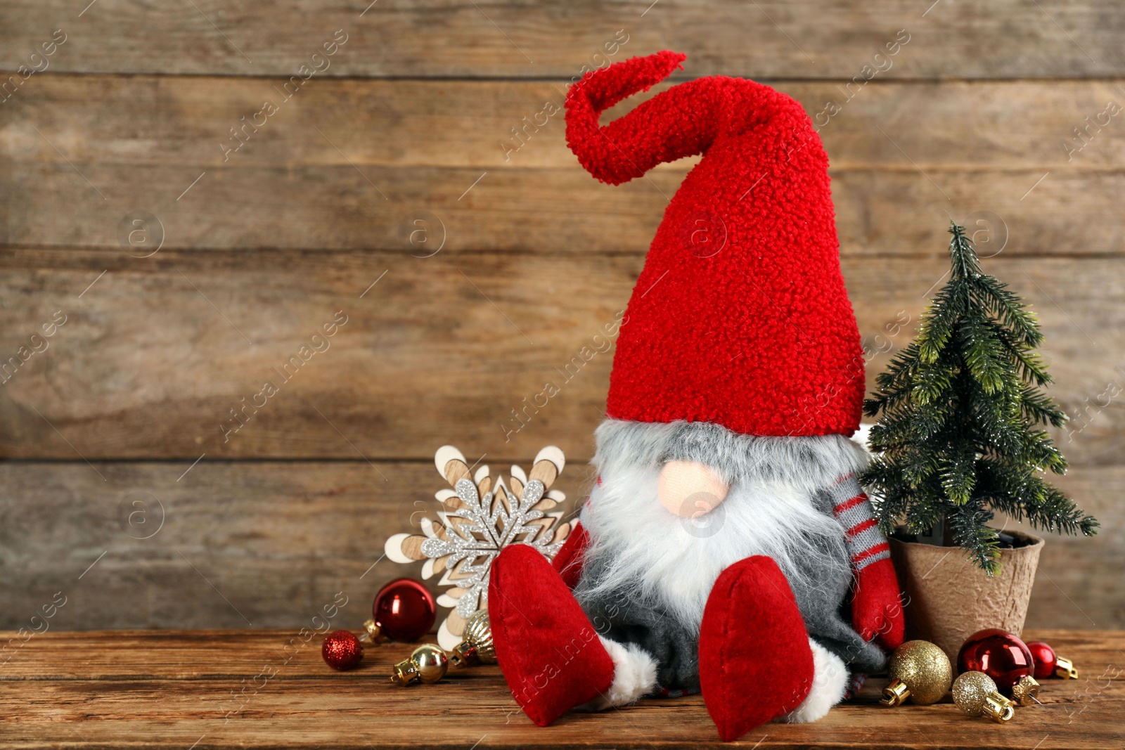 Photo of Cute Christmas gnome and festive decor on table against wooden background. Space for text