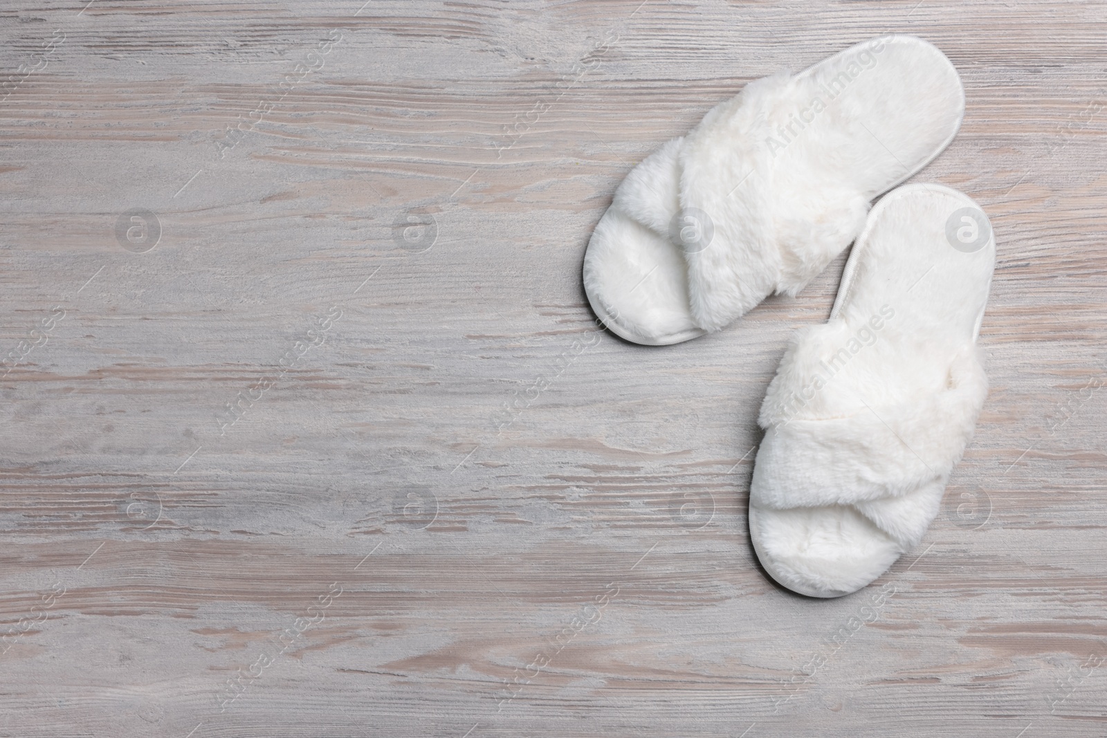 Photo of Pair of soft slippers on white wooden floor, top view. Space for text