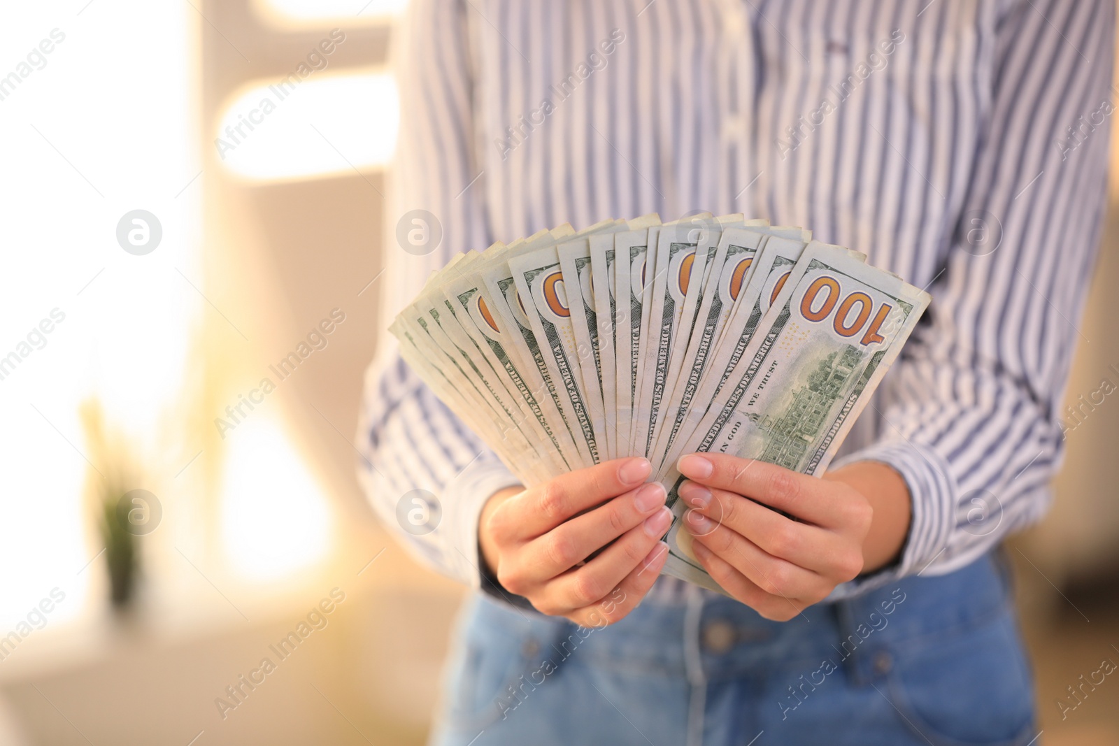 Photo of Young woman holding dollar bills on blurred background, closeup