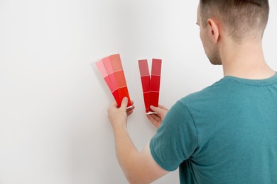 Photo of Man with palette choosing color for painting wall indoors. Interior design