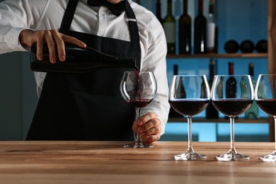 Photo of Bartender pouring wine into glass at counter in restaurant, closeup