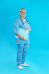 Mature doctor with stethoscope and clipboard on blue background