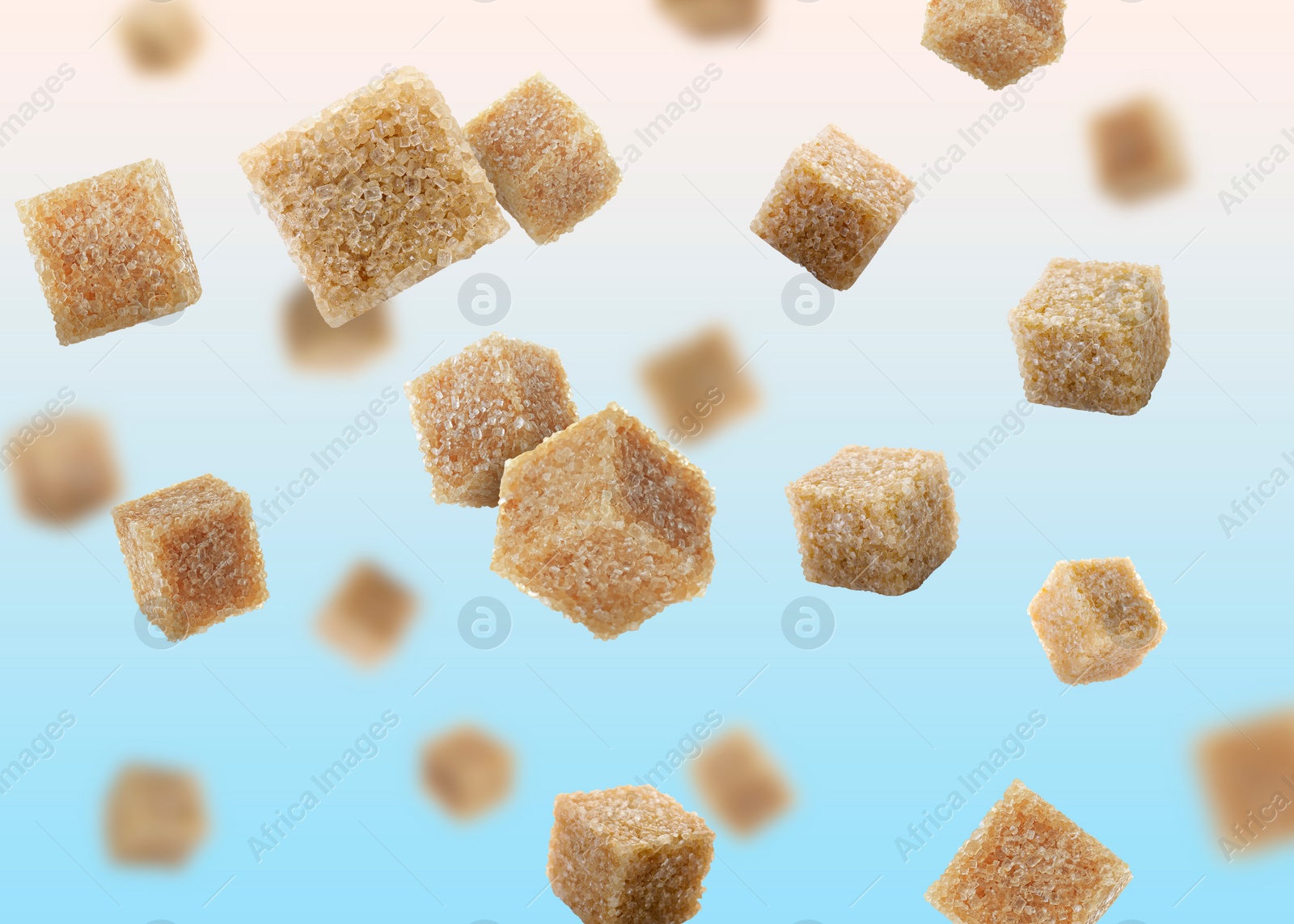 Image of Brown cane sugar cubes falling on light blue gradient background