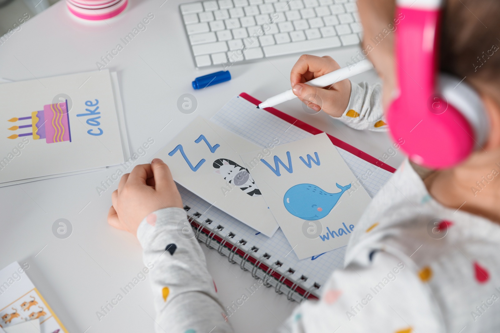 Photo of Little girl learning English at home, closeup