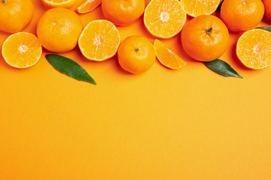 Photo of Flat lay composition with fresh ripe tangerines and space for text on orange background. Citrus fruit