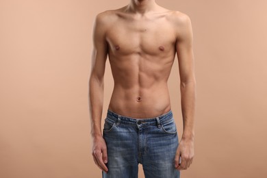 Shirtless man with slim body on beige background, closeup