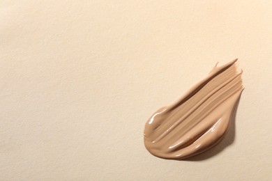 Photo of Swatch of skin foundation on beige background, top view. Space for text