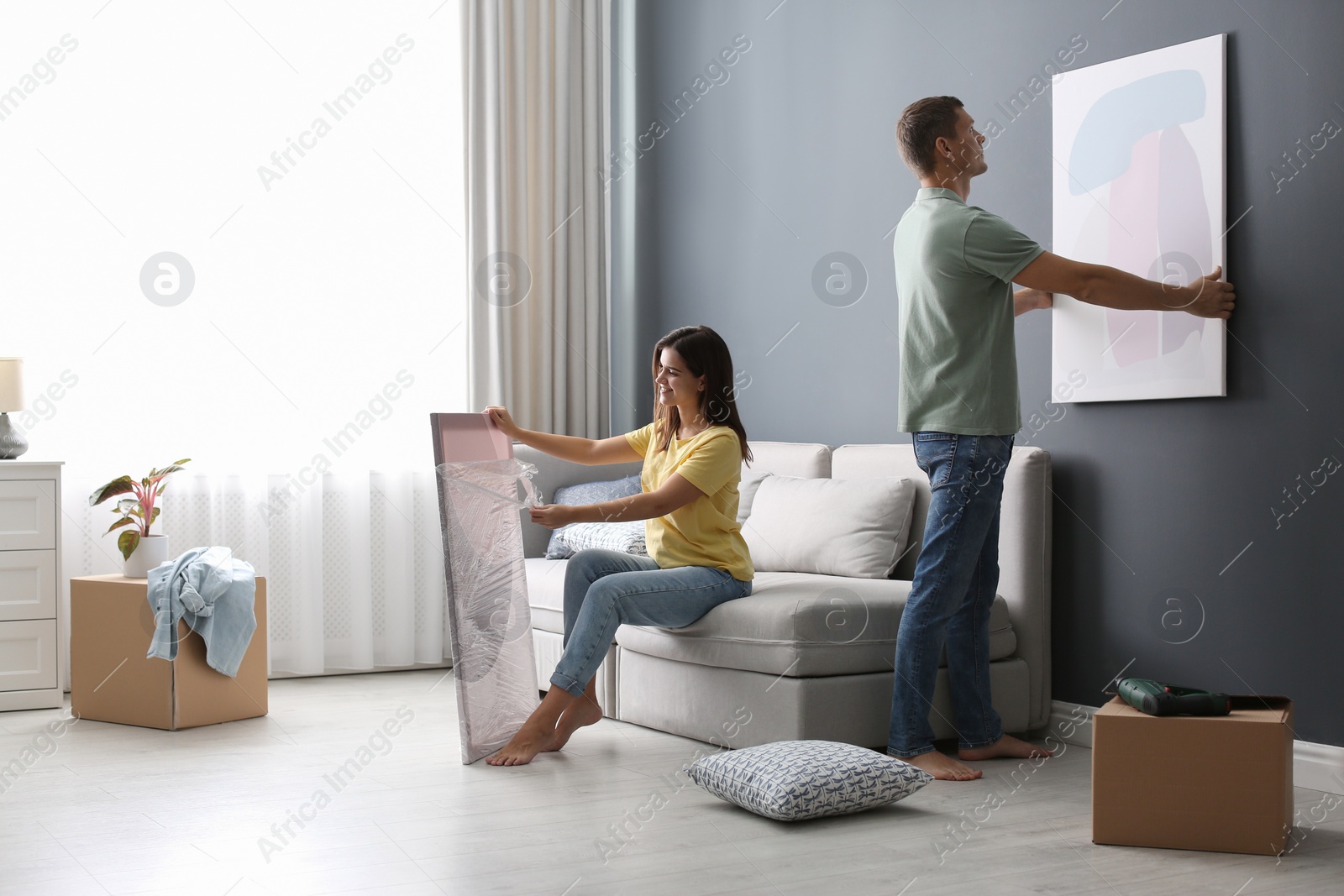 Photo of Couple decorating room with pictures together. Interior design