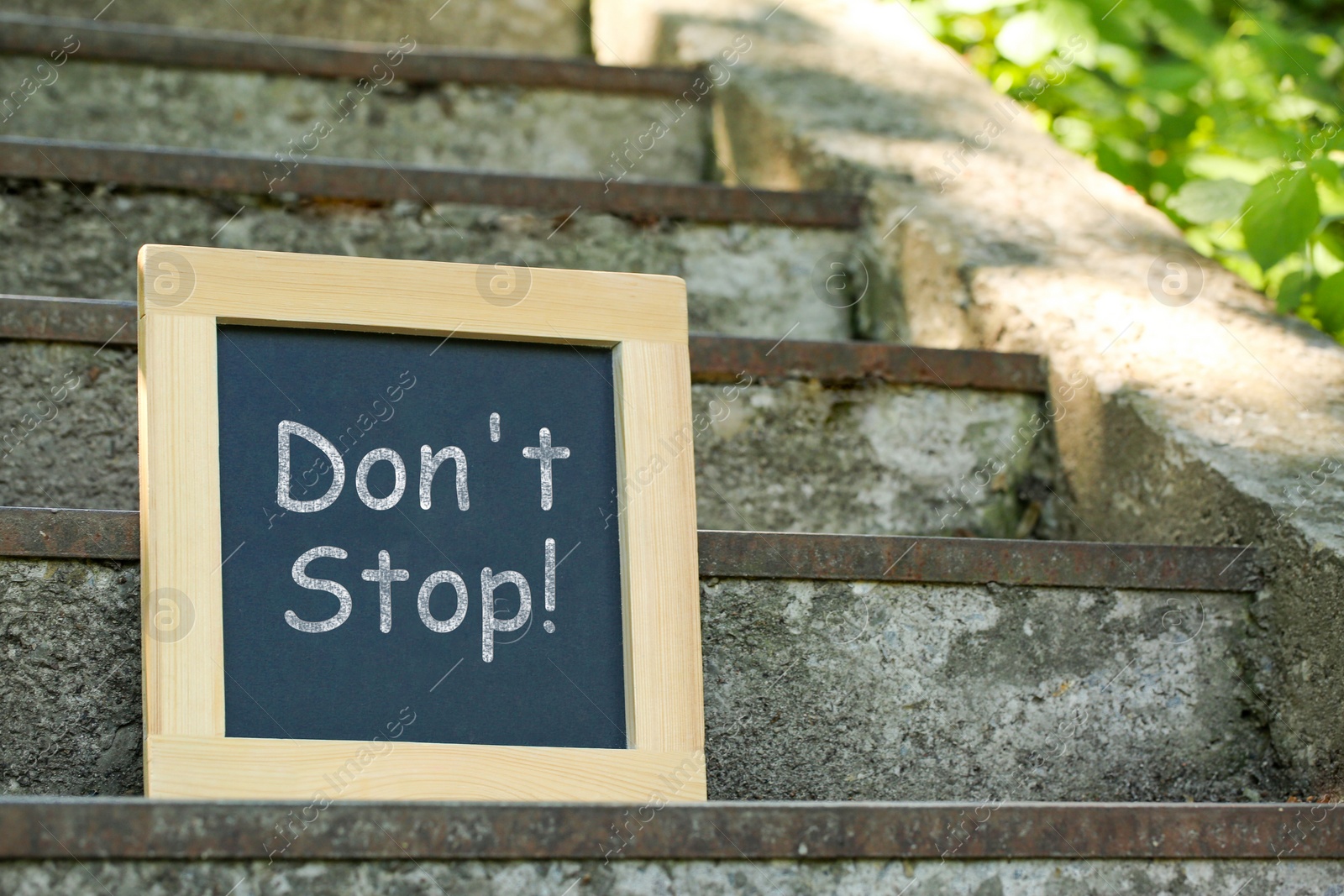 Photo of Chalkboard with phrase Don't Stop on stone stairs outdoors, space for text