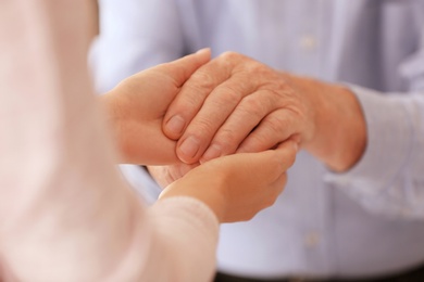 Photo of Young woman holding elderly man hand, closeup. Help service