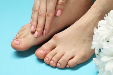 Photo of Woman with neat toenails after pedicure procedure on light blue background, closeup