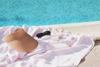 Photo of Pink blanket with different beach accessories near outdoor swimming pool on sunny day