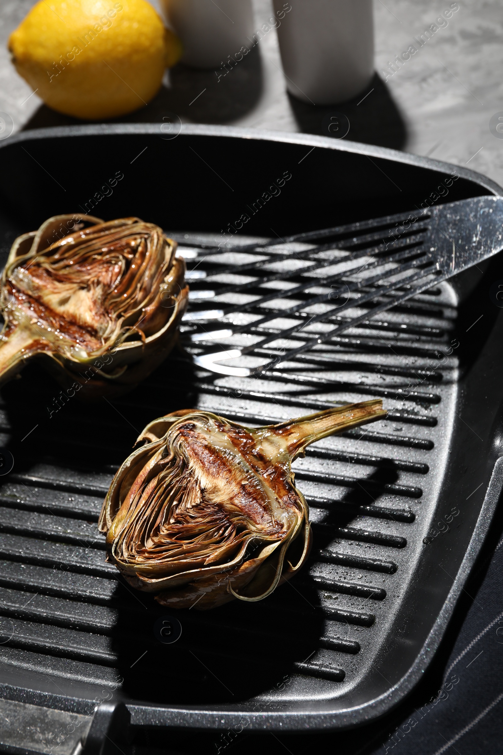 Photo of Pan with tasty grilled artichokes on table, closeup