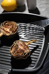 Pan with tasty grilled artichokes on table, closeup