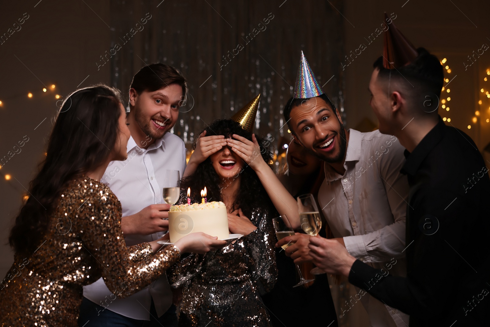 Photo of Happy friends with tasty cake and glasses of sparkling wine celebrating birthday indoors